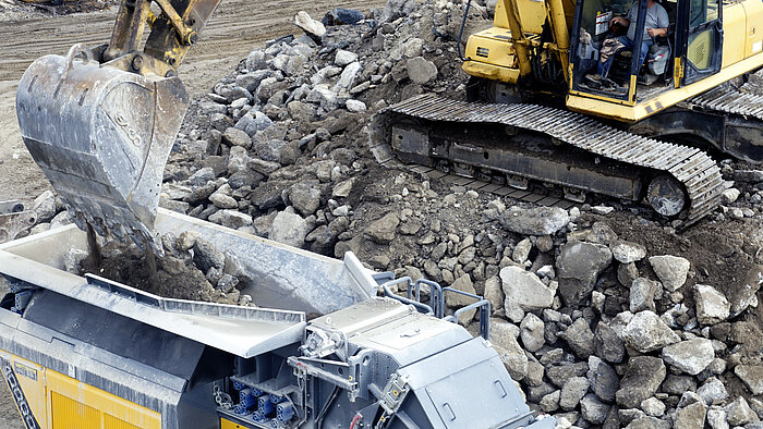 Crusher feed hopper being fed by an excavator