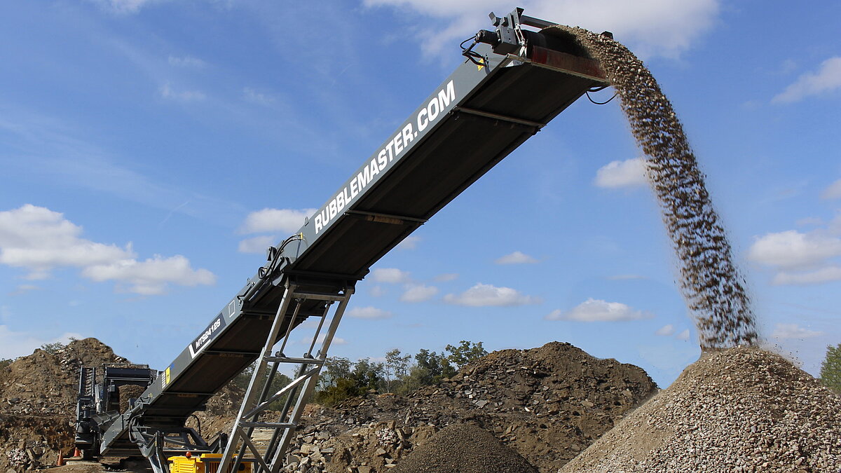 Tracked stacking conveyor moving material discharged from a RUBBLE MASTER crusher
