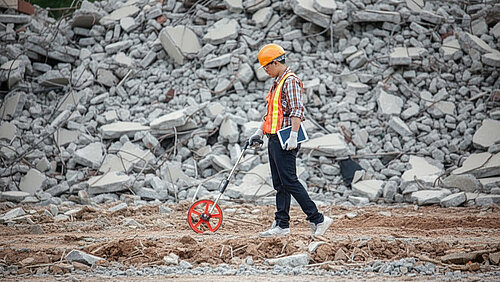Guy Pushing a Measuing Wheel over Rough Terrain